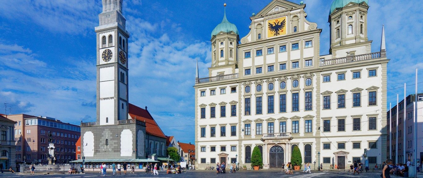 Das Augsburger Rathaus und der Perlachturm unter klarem Himmel.