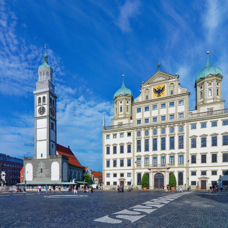 Das Augsburger Rathaus und der Perlachturm bei klar blauem Himmel.