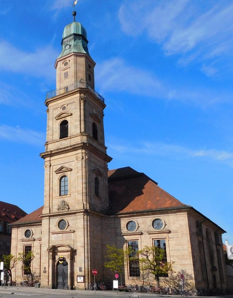 Historisches Gebäude mit Uhrturm und blauem Himmel im Hintergrund.