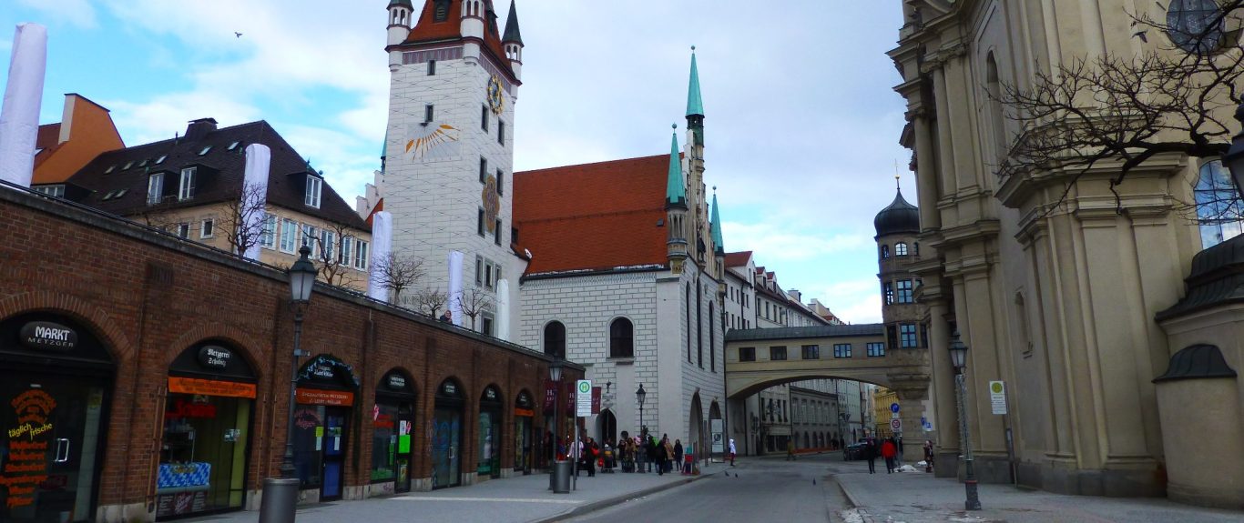 Stadtansicht mit historischen Gebäuden und einer Straße, die zu einem Platz führt.